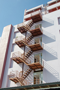 外部走火楼梯现代建筑的外部楼梯工人在户外楼梯上焊接金属扶手, 焊接