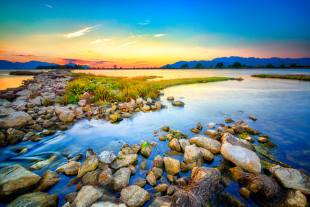 美丽的夏天落日海边多岩石的海岸。Hdr ima