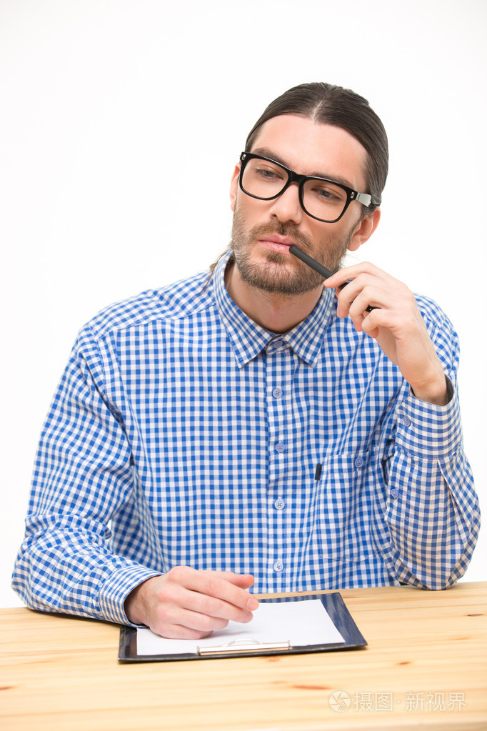 思维的年轻人在眼镜坐在办公桌前