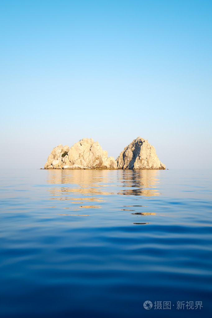 在晴朗的天空背景上大海里的石头