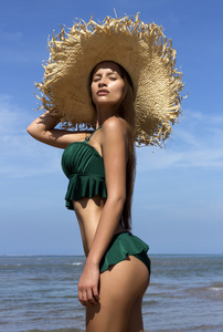 海滩上戴帽子的女人。 漂亮的漂亮姑娘，穿绿色的自行车