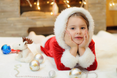 小女孩打扮成圣诞老人，在壁炉旁