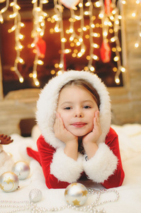 小女孩打扮成圣诞老人，在壁炉旁