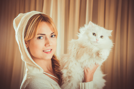 女孩拿着一只毛茸茸的白色猫