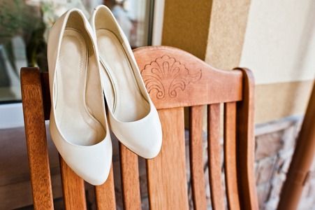 在木椅上的新娘的奶油婚礼鞋子
