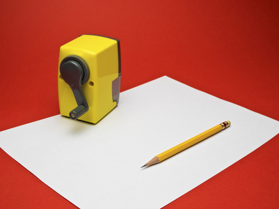 黄色的铅笔和卷笔刀红色背景的白板纸