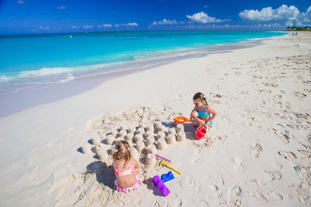 在热带度假期间玩沙滩玩具的小女孩