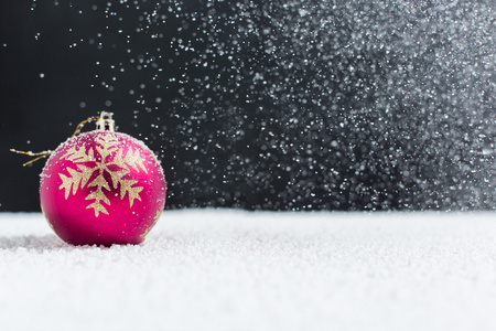圣诞球在雪地上，飘落的雪花