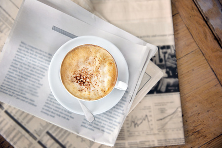 杯美味的卡布奇诺咖啡和报纸在桌子上