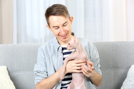 年轻英俊的男人，在家里的沙发上抱着只猫