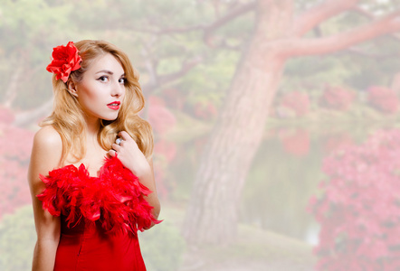 美丽的年轻女子，穿着红色，花园的花朵背景