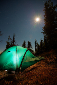 用在夜晚森林中的光照亮的帐篷