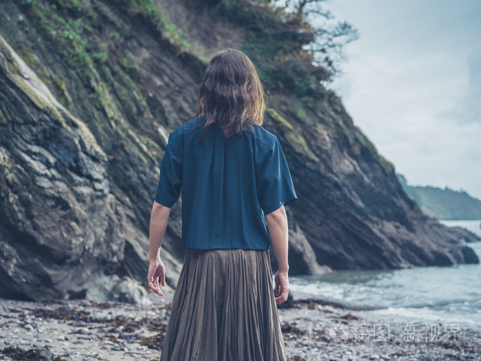 年轻女人站在悬崖上海滩