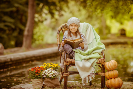 读一本书在户外的女孩。休息休息在秋天的公园里的孩子