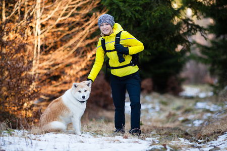在冬季森林和狗一起徒步旅行的女人