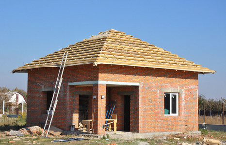 屋顶膜覆盖木制建筑家框架带有屋顶椽子和金属梯户外蓝天的衬托。屋面施工外墙红砖房子墙立面