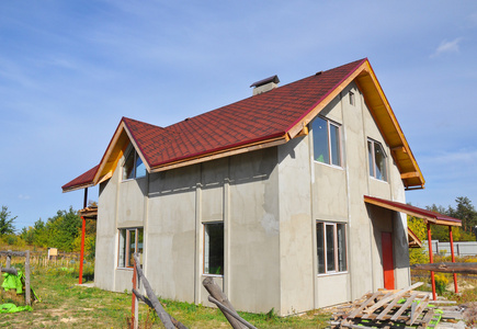 新房子的屋顶上覆盖着沥青瓦。 沥青剥落屋顶的优点。 屋顶建筑和建筑房屋的立面外观。 在屋顶安装修补沥青瓦