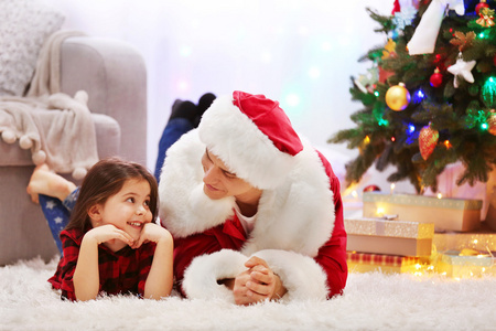 快乐的父亲和女儿在装饰圣诞房间的地板上