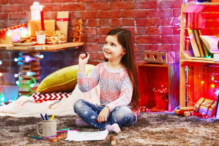漂亮的小女孩在圣诞画装饰的房间