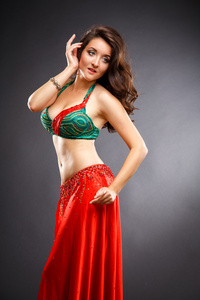 美丽的肚皮舞者在华丽的红色和绿色的服装礼服年轻女子