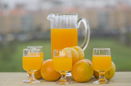 杯美味橙汁和在花园里的桌子上的橘子