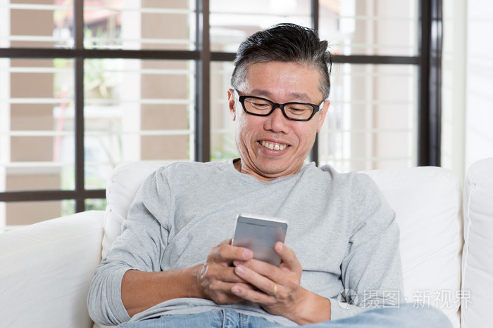 成熟的亚洲男人在智能手机上发短信