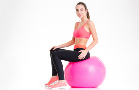 快乐迷人的年轻女运动员坐在粉红色的健身器上