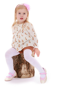 小女孩坐在一个树桩上