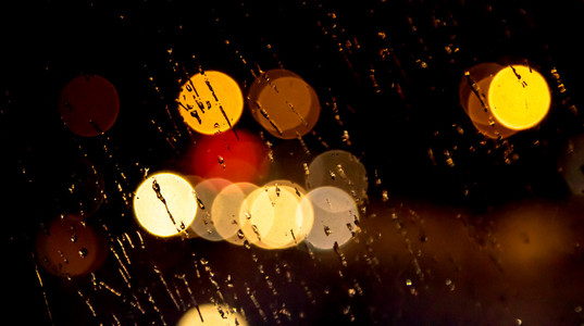 抽象的夜城光和景通过汽车挡风玻璃上覆盖在雨中