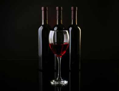 葡萄酒对成一排在深红色背景瓶玻璃，关闭了