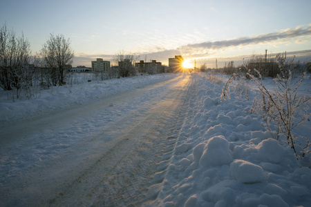 日落时通往房子的冬季公路
