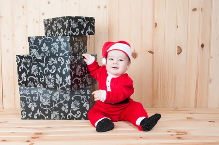 在圣诞节在谷仓里穿着圣诞老人服装和帽子的小宝贝