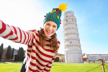 在考虑自拍照在比萨的圣诞树帽子的女人