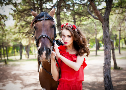 美丽的小姐穿了红衣服，骑着马在阳光明媚的 s