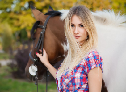 美丽的小姐穿着 t 恤和牛仔裤骑在一匹马