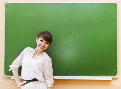 女学生站在旁边干净黑板在教室里