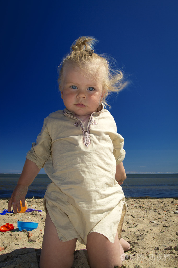 小女孩玩在海边沙滩上的沙子