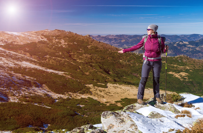 女性的徒步旅行者站在雪岩仰慕山风景冬天太阳