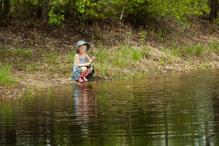 小女孩在森林中的湖面上钓鱼