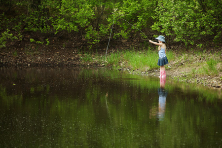 小女孩在森林中的湖面上钓鱼