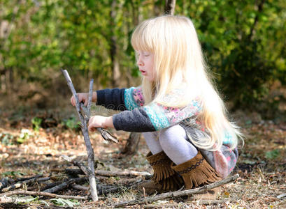 可爱的金发女孩在地上玩树枝