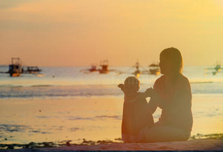 日落海滩上的母亲和小女儿