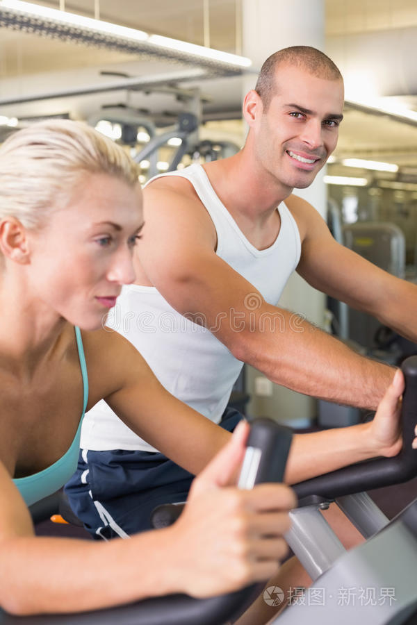 健身的年轻夫妇在健身房练习自行车
