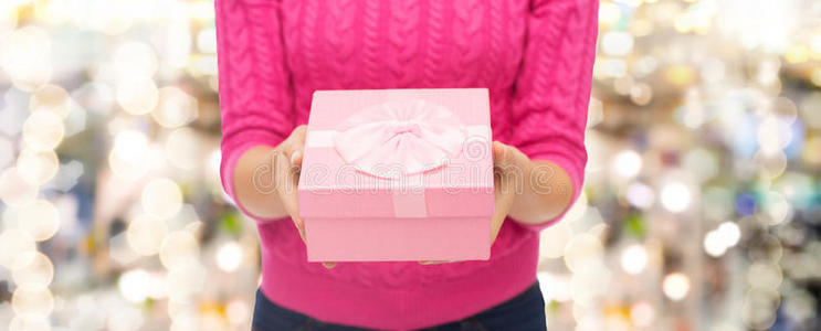 一个穿着粉红色毛衣的女人拿着礼品盒的特写镜头