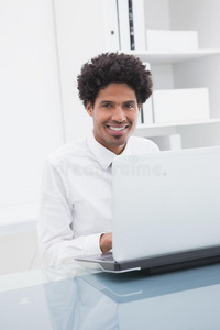 微笑的商人坐着用笔记本电脑