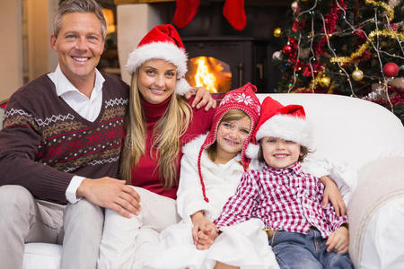一个微笑的家庭在圣诞节坐在沙发上的画像