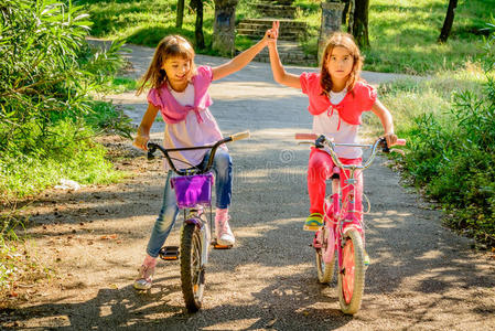 两个小女孩骑着自行车互相玩耍.照片