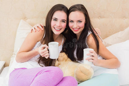 漂亮的朋友在床上喝咖啡