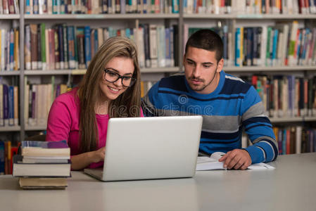 快乐的学生在图书馆用笔记本电脑工作