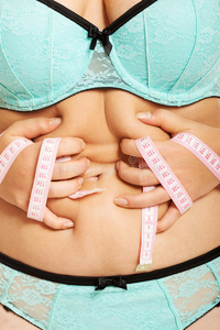 超重妇女测量她的胖肚子